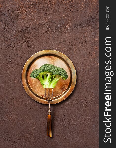 Broccoli on the vintage metal plate on the brown textured table, concept of healthy eating, top view