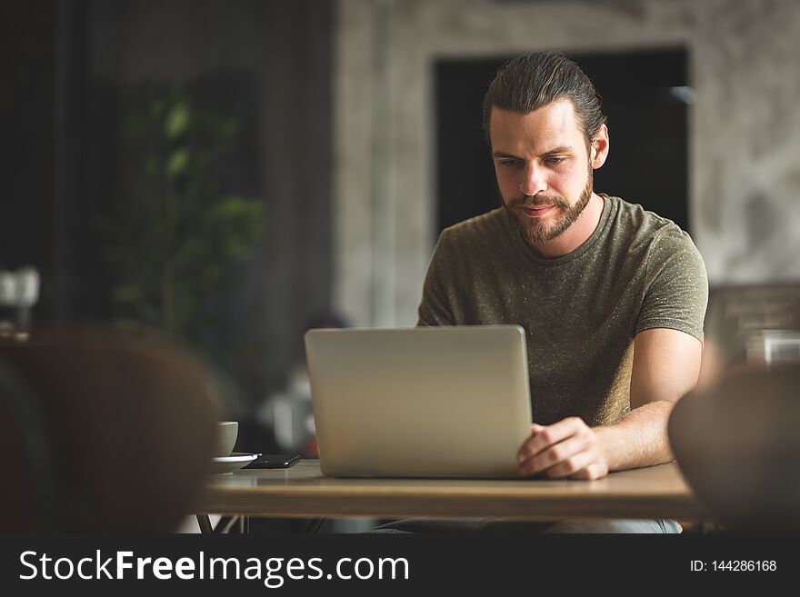 Bearded Male freelancer working on laptop computer at the coffee shop