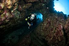 Scuba Diver Swimms Through A Hole In The Wall Stock Photo Scuba Diver Swimms Through A Hole In The Wall Stock Photo