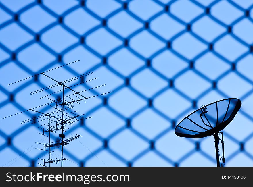 Wire fence with satellite in blue sky