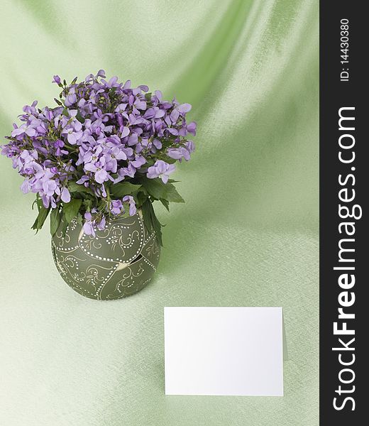 Flowers are in a vase and empty memo card with space for your own text, over green background