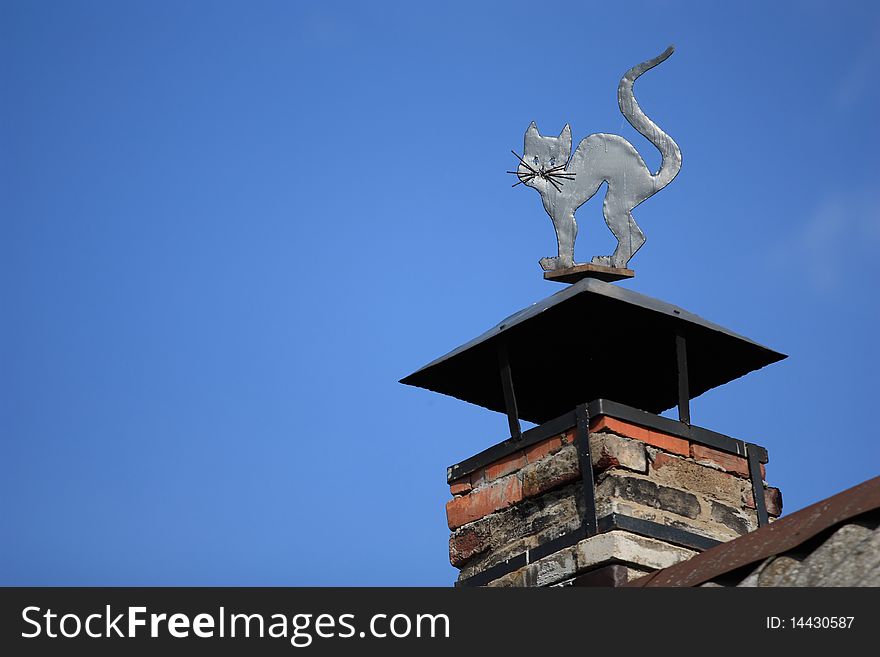 Chimney decorated with a metal cat on the roof on an old-style russian village house. Chimney decorated with a metal cat on the roof on an old-style russian village house