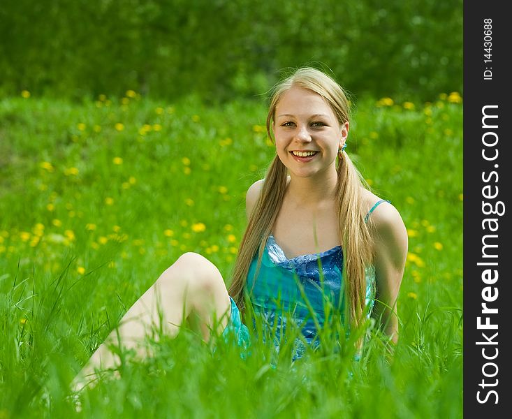 Pretty smiling blonde girl relaxing in grass outdoor. Pretty smiling blonde girl relaxing in grass outdoor