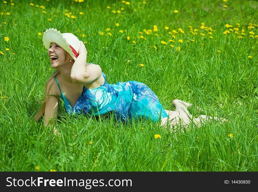 Pretty smiling  girl in hat relaxing in grass outdoor