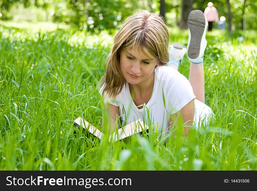 Young girl is laying on the grass with a book. Young girl is laying on the grass with a book