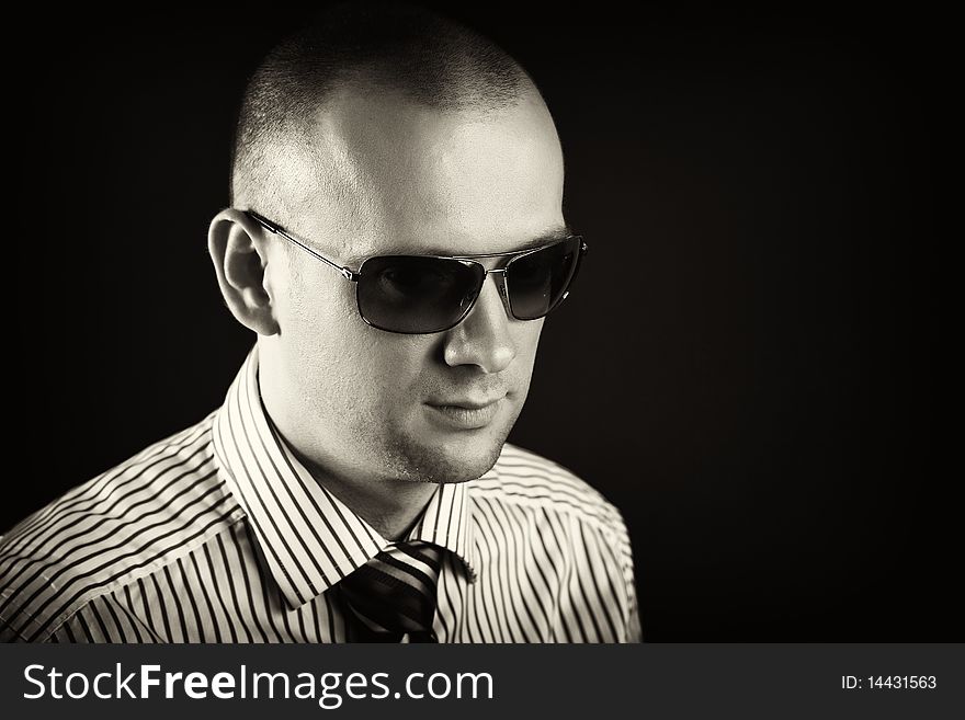 Young man with sunglasses posing on a black background