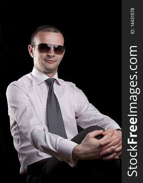 Young man with sunglasses posing on a black background. Young man with sunglasses posing on a black background