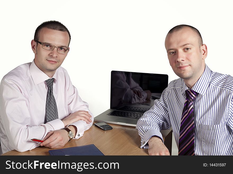 Two businessmen looking at camera with laptop behind. Two businessmen looking at camera with laptop behind