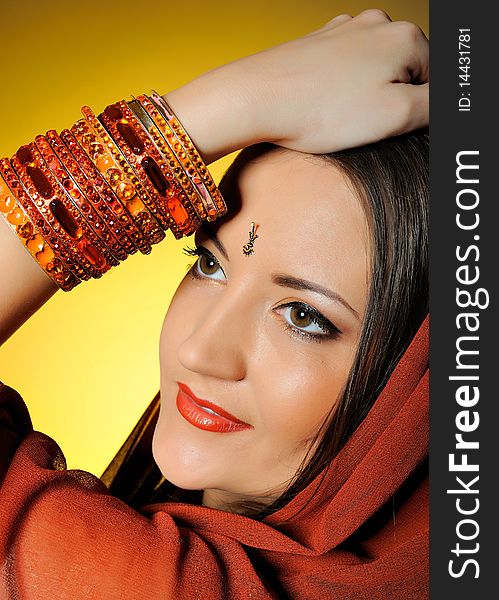 Young beautiful woman in indian traditional jewellary, bindi and sari dress. yellow background. Young beautiful woman in indian traditional jewellary, bindi and sari dress. yellow background