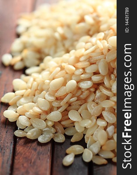 A small heap of sesame on wood background, macro shot.