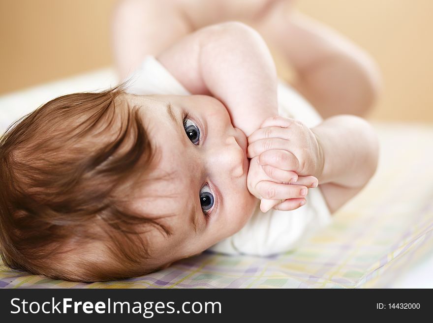 Cute baby boy with hands in mouth; shallow DOF, focus on eyes