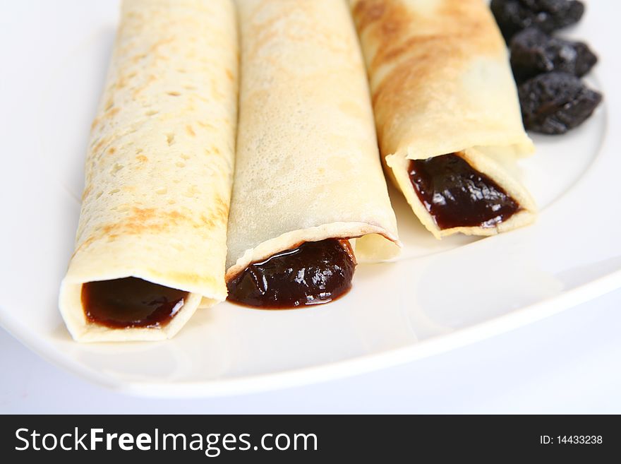 Pancakes stuffed with prune jam decorated with dried plums on a plate