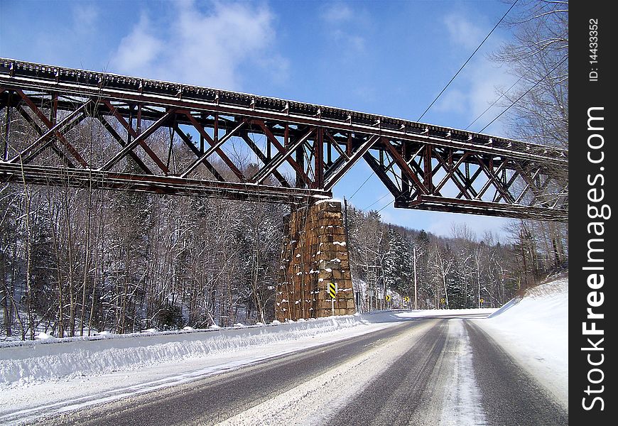 Train trestle bridge goes over the road after a new snow storm. Train trestle bridge goes over the road after a new snow storm