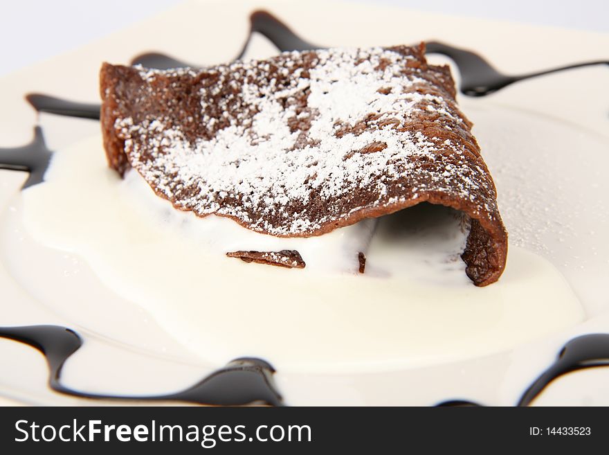 Chocolate pancake with homogenized cheese covered with caster sugar decorated with chocolate sauce