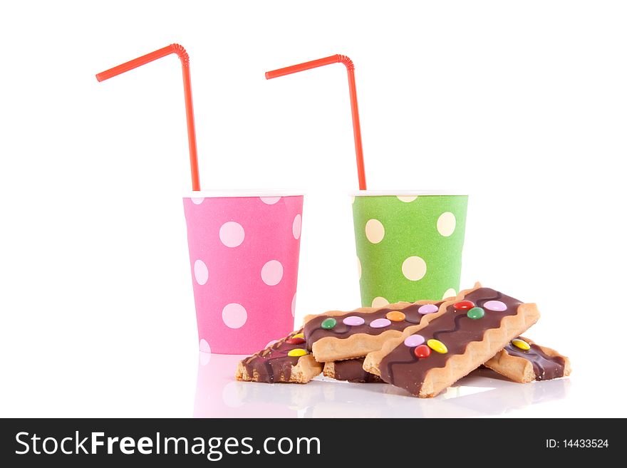 Two colored drinking cups with straws and cookies isolated over white