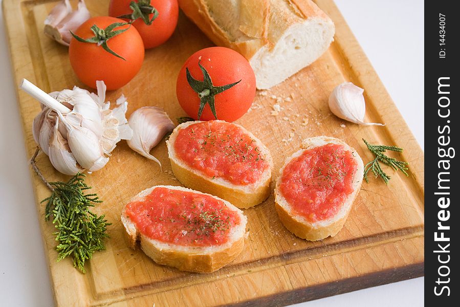 Slices of bread with a tomato paste, parsley and tomatoes with garlic on a kitchen board. Slices of bread with a tomato paste, parsley and tomatoes with garlic on a kitchen board.