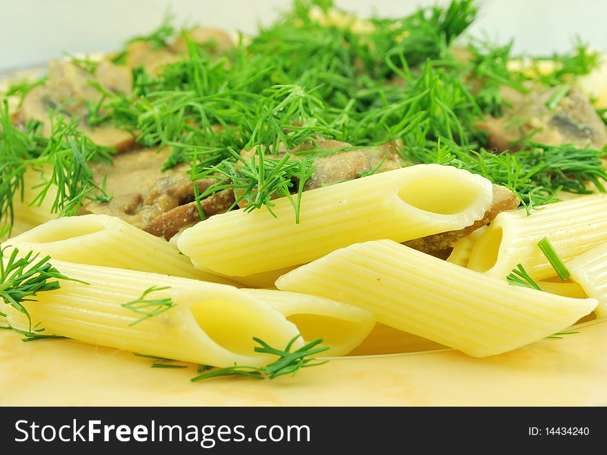 Close up of penne pasta, mushrooms and dill decoration