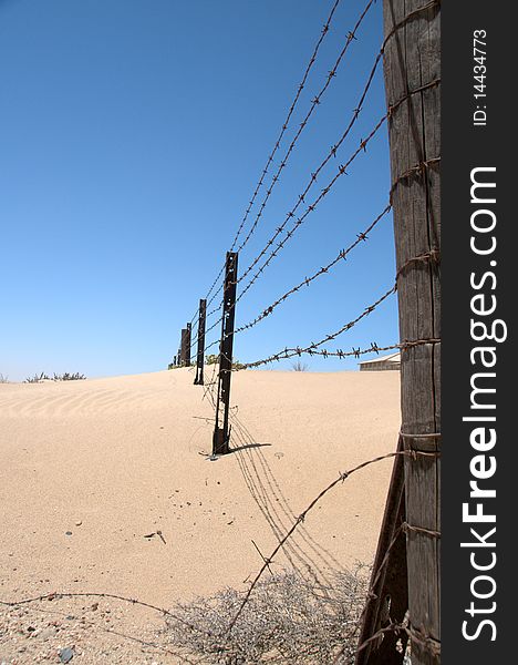 Old barbed wire fence in the desert with blue sky, Namibia.