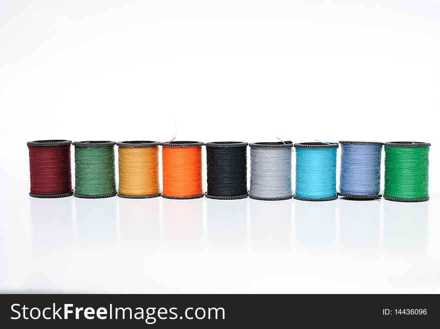 Colorful thread spools lined up on a white background. Colorful thread spools lined up on a white background.