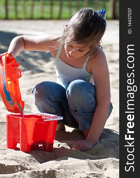 Girl playing in a sand pit in a beautiful summer day