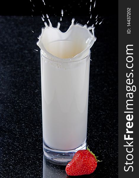 Strawberry splashing in glass of milk. Strawberry splashing in glass of milk