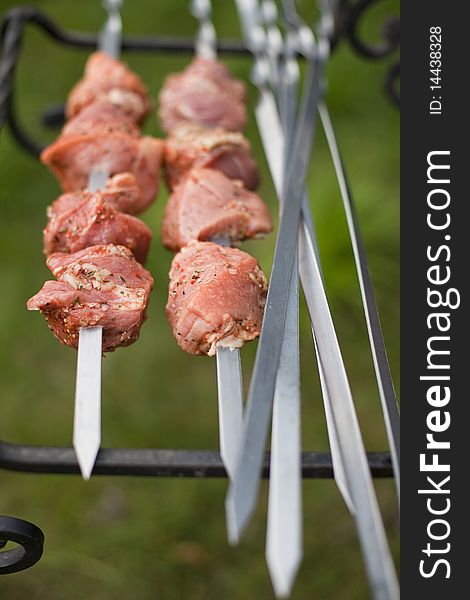 Marinated meat being prepared for cooking on metal skewers