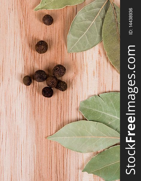 Spices: aromatic pepper and bay leaves closeup on wooden background
