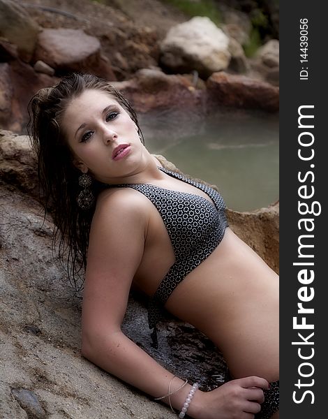 A young woman leaning back in her swimsuit on a rock. A young woman leaning back in her swimsuit on a rock.