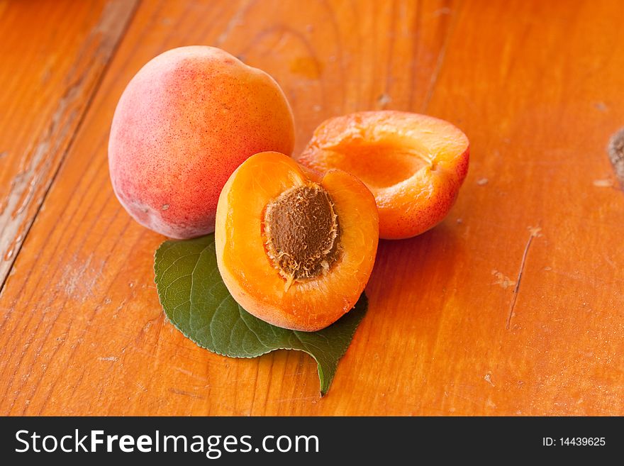 Apricots and leaf on wooden background
