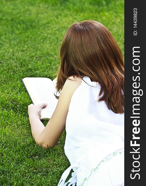 Young beautiful girl reading a book outdoor