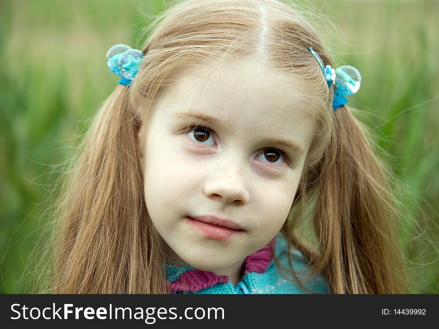 A little girl on a green meadow dressed warmly in a cold summer day