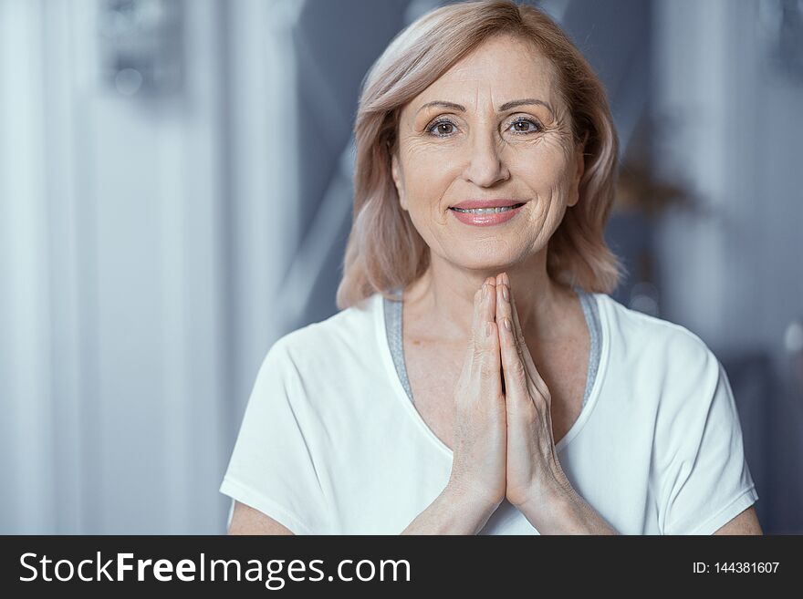 Smiling Middle-Aged Woman Gestures As A Posture Of Prayer. Calm Cheerful Woman With Praying Hands Looks At Camera. Portrait. Namaste. Smiling Middle-Aged Woman Gestures As A Posture Of Prayer. Calm Cheerful Woman With Praying Hands Looks At Camera. Portrait. Namaste.