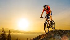 Cyclist In Red Riding The Bike Down The Rock At Sunrise. Extreme Sport And Enduro Biking Concept. Royalty Free Stock Photography