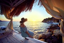 Free Woman In Hat Relaxing By The Sea In A Luxurious Beachfront Hotel Resort At Sunset Enjoying Perfect Beach Holiday Vacation In Stock Image - 144391251