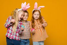 Two Little Girls And Boy With Easter Bunny Ears Holding Colorful Eggs Stock Photo
