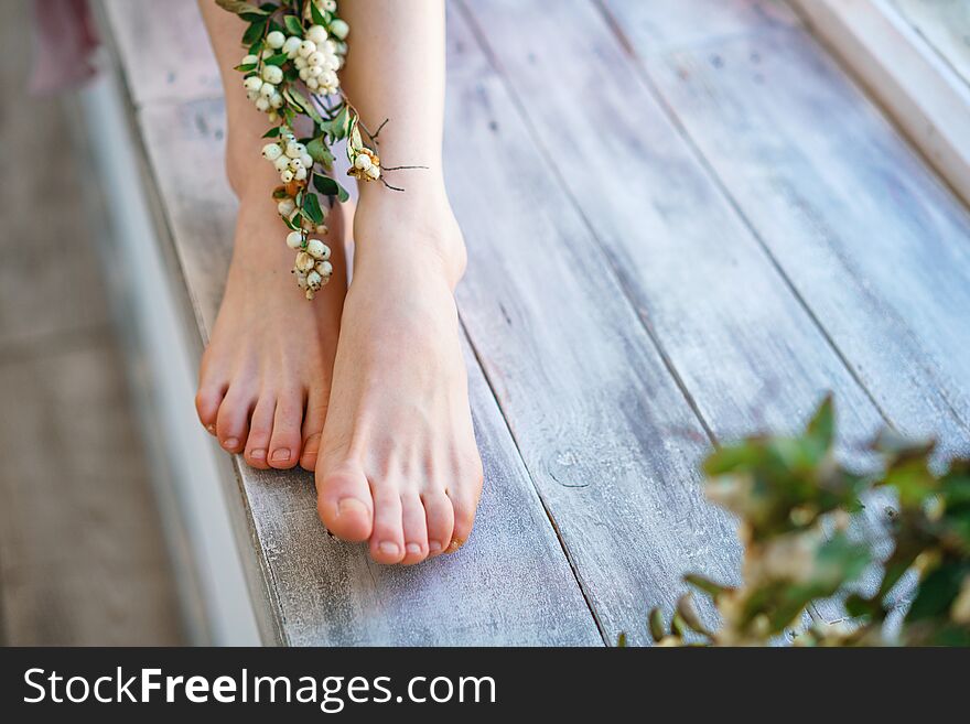 Beautiful women`s feet with flowers on wooden background, foot skin care