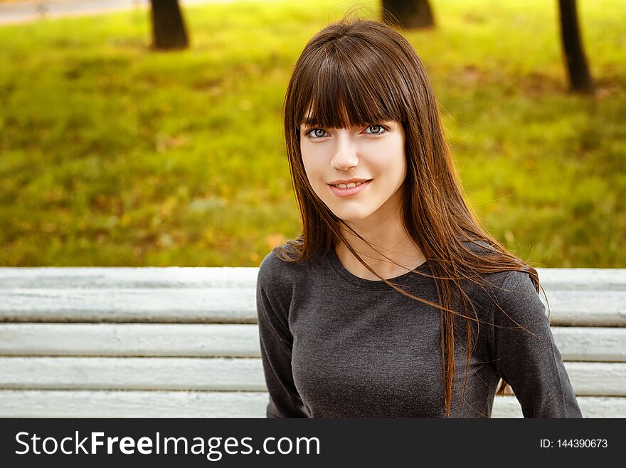 Portrait of a young woman sitting in the Park on a bench.