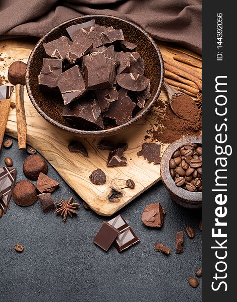 Dark or milk organic chocolate pieces and truffle candies in wooden bowl on dark concrete backgound