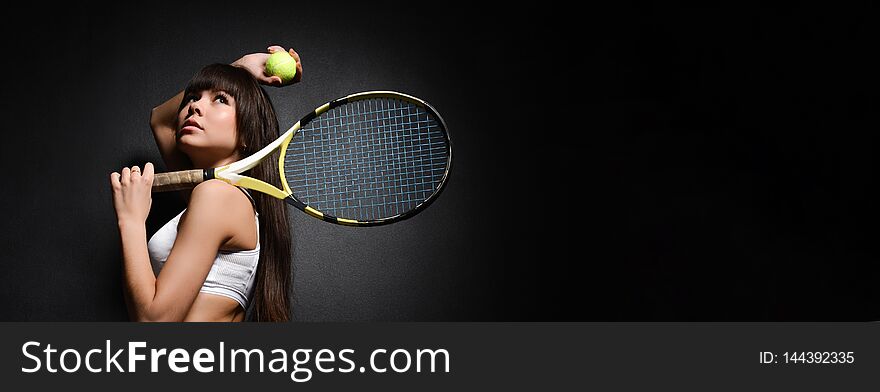 Portrait of a girl tennis player tennis racket in white uniform clothes on a dark background. Studio shot. Portrait of a girl tennis player tennis racket in white uniform clothes on a dark background. Studio shot.
