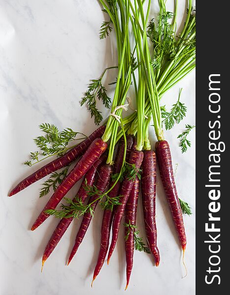 Overhead view of a fresh, organic bunche of purple carrots on a marble surface. Overhead view of a fresh, organic bunche of purple carrots on a marble surface