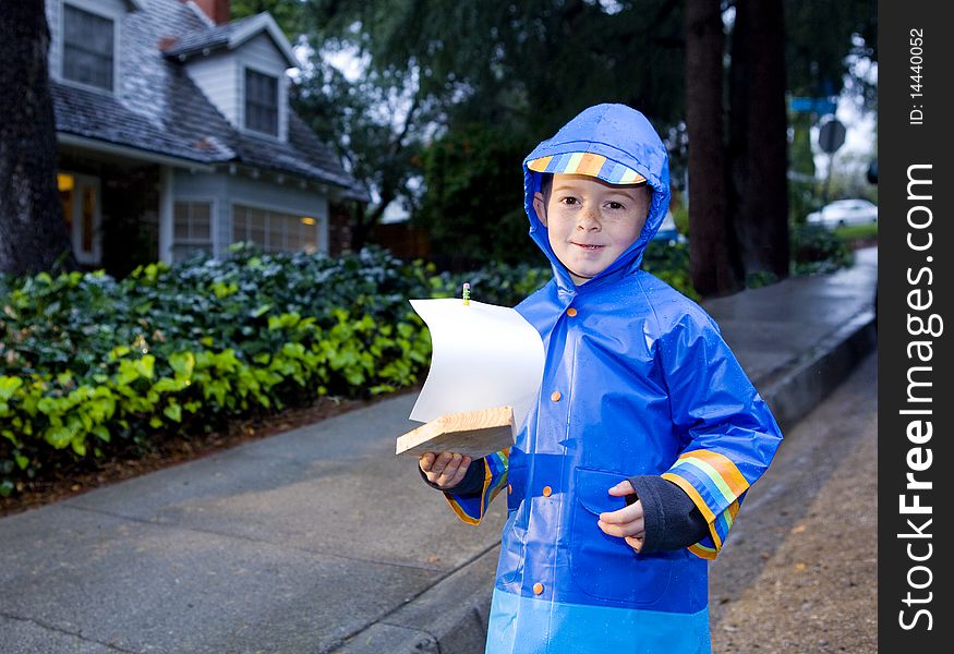 Young boy playing with toy boat in the rain 2