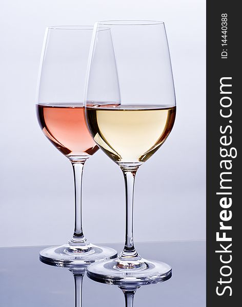 Elegant crystal wine glasses filled with pink and white wine. Elegant crystal wine glasses filled with pink and white wine.