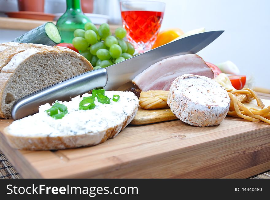 Meal concept with bread, onion, tomatoes, cheese, wine, bacon and pepper.