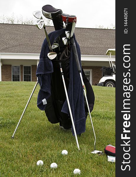 Golfer sets his clubs next to the green to practice. Golfer sets his clubs next to the green to practice