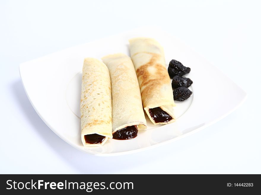 Pancakes stuffed with prune jam decorated with dried plums on a plate. Pancakes stuffed with prune jam decorated with dried plums on a plate