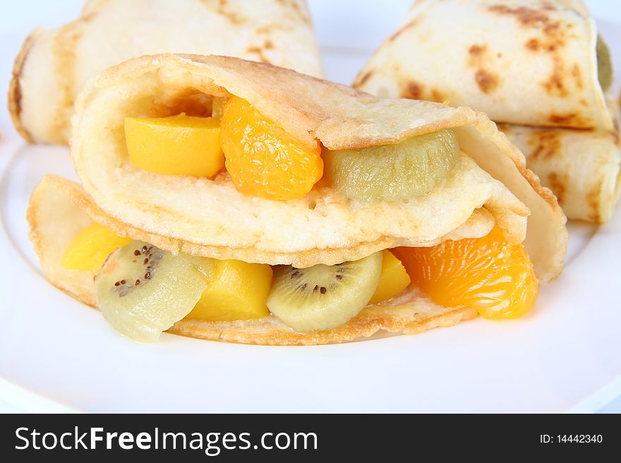 Pancakes stuffed with fruit (peach, kiwi, mandarin) on a plate. Pancakes stuffed with fruit (peach, kiwi, mandarin) on a plate