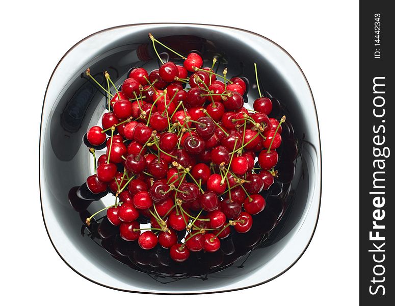 Fresh ripe cherry berry in black glass dish isolated on white