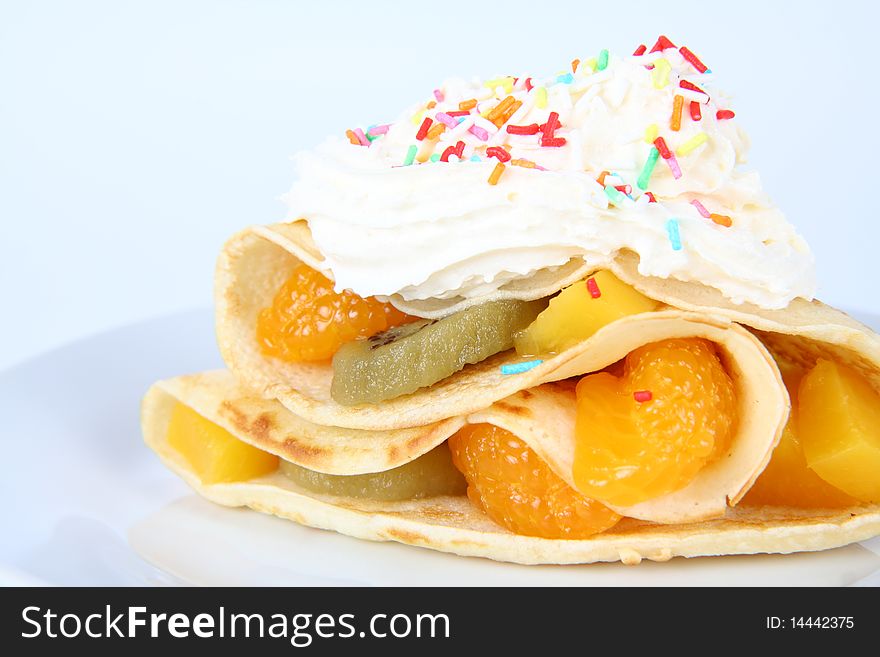 Pancake stuffed with fruit (peach, kiwi, mandarin) with whipped cream and colorful sprinkles. Pancake stuffed with fruit (peach, kiwi, mandarin) with whipped cream and colorful sprinkles