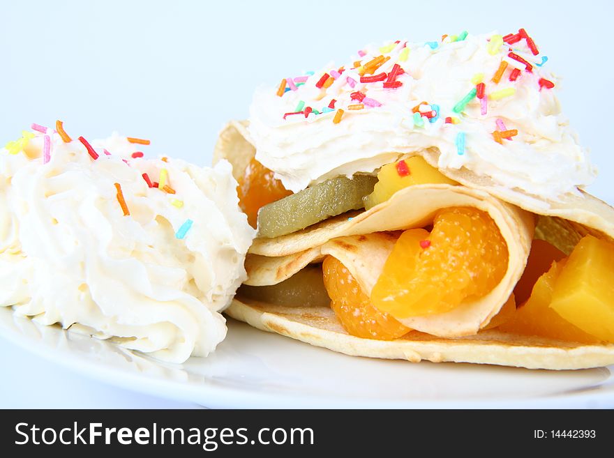 Pancake stuffed with fruit (peach, kiwi, mandarin) with whipped cream and colorful sprinkles. Pancake stuffed with fruit (peach, kiwi, mandarin) with whipped cream and colorful sprinkles