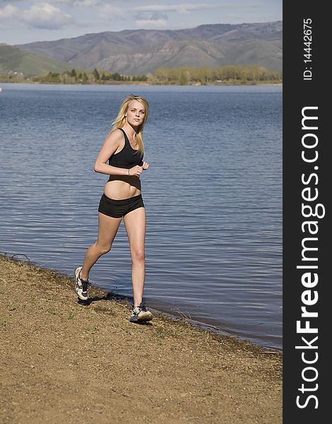 A woman is running on the beach wearing black shorts and a halter top. A woman is running on the beach wearing black shorts and a halter top.